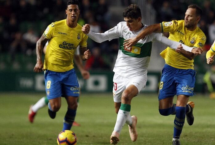 El jugador del Elche Gonzalo Villar controla un balón ante dos jugadores de la UD Las Palmas / LFP