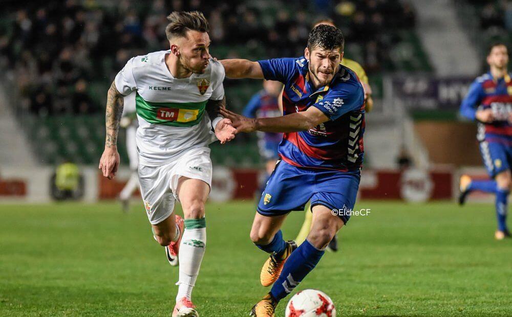 El jugador del Elche Josan pelea un balón ante un jugador de la Llagostera / Sonia Arcos - Elche C.F.